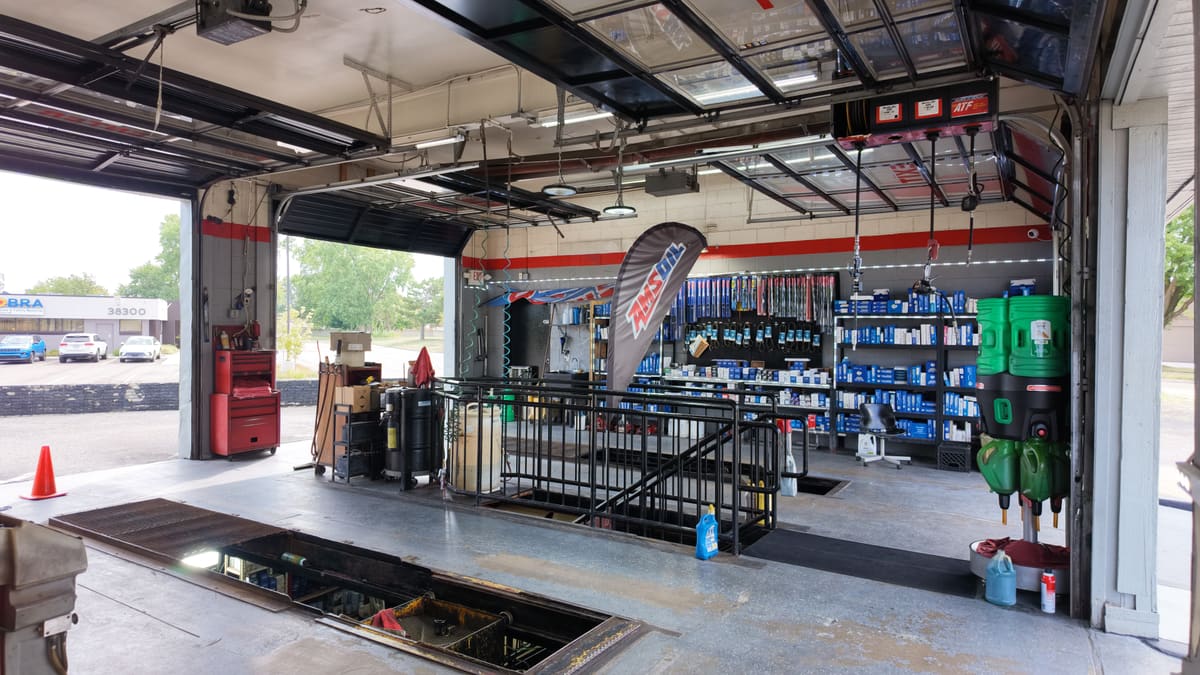 Open drive-up service bay at Sterling Quick Lube in Sterling Heights, Michigan, with the oil change pit and shelves of motor oil and filters